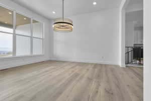 Unfurnished dining area with light wood finished floors, a chandelier, and recessed lighting