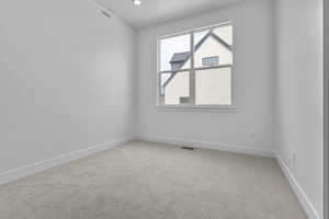 Carpeted spare room featuring baseboards