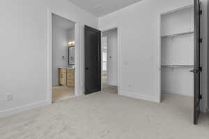 Unfurnished bedroom with light carpet and connected bathroom