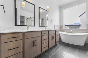 Bathroom with double vanity, dark tile patterned floors, a soaking tub, a shower stall, and tile walls