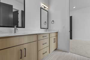 Bathroom featuring double vanity, light carpet, and recessed lighting