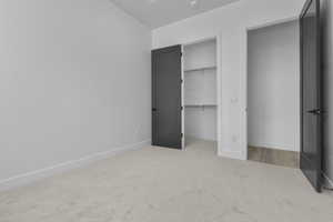 Unfurnished bedroom with light carpet and a spacious closet