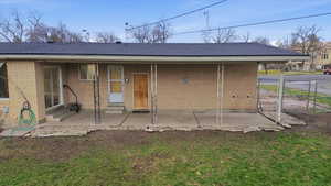 Rear view of property featuring covered patio, a shingled roof and brick exterior