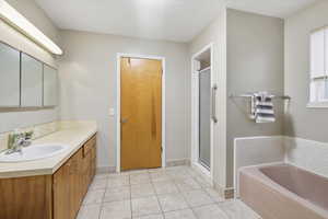 Bathroom with extra long vanity, a stall shower, light tile patterned floors, a separate bathtub