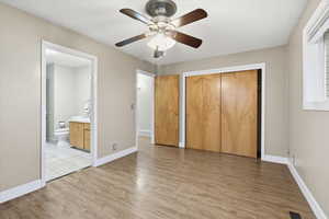 Unfurnished bedroom featuring light wood-style flooring, a closet, connected bathroom, and ceiling fan