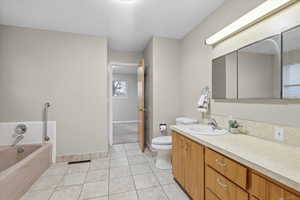Bathroom featuring a garden tub, vanity, a textured ceiling, and light tile patterned floors
