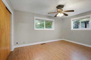 Unfurnished bedroom featuring a closet, light wood-style flooring, a ceiling fan, and multiple windows