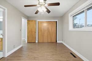 Unfurnished bedroom featuring a closet, light wood-style floors, a ceiling fan, and connected bathroom