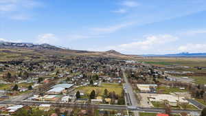 Aerial view of property and surrounding area featuring mountains and nearby schools.