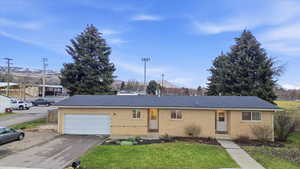 Ranch-style home featuring brick siding, driveway, with additional parking, a garage, a front yard, and roof with shingles