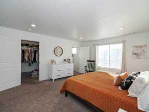 Bedroom with a spacious closet, carpet flooring, recessed lighting, and a textured ceiling