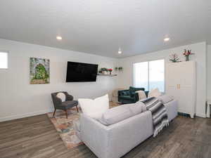 Living area featuring healthy amount of natural light, recessed lighting, dark wood-type flooring, and a textured ceiling