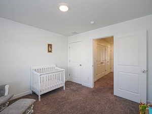 Bedroom featuring a crib and dark carpet