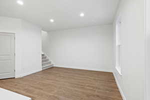 Basement with recessed lighting, light wood finished floors, and stairs
