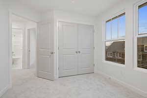 Unfurnished bedroom featuring light colored carpet and a closet