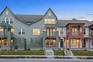 View of front of home with roof with shingles, stucco siding, a front yard, and a balcony