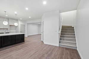Kitchen featuring hanging light fixtures, recessed lighting, light wood-style floors, white cabinets, and light stone counters