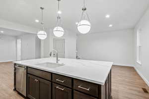 Kitchen with dark brown cabinetry, open floor plan, recessed lighting, pendant lighting, and light wood-style flooring