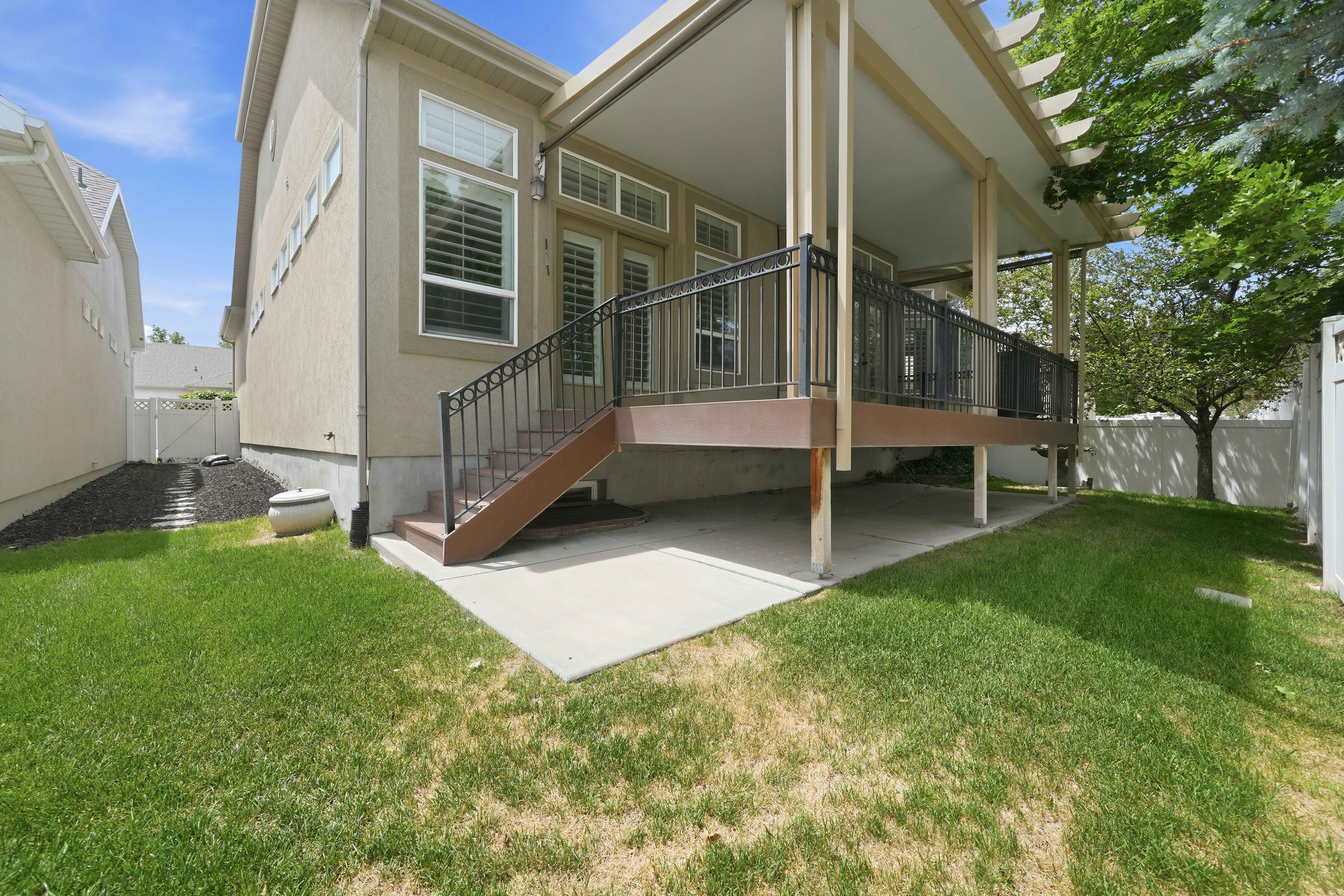 Elevated deck with black metal railings, leading to a concrete patio