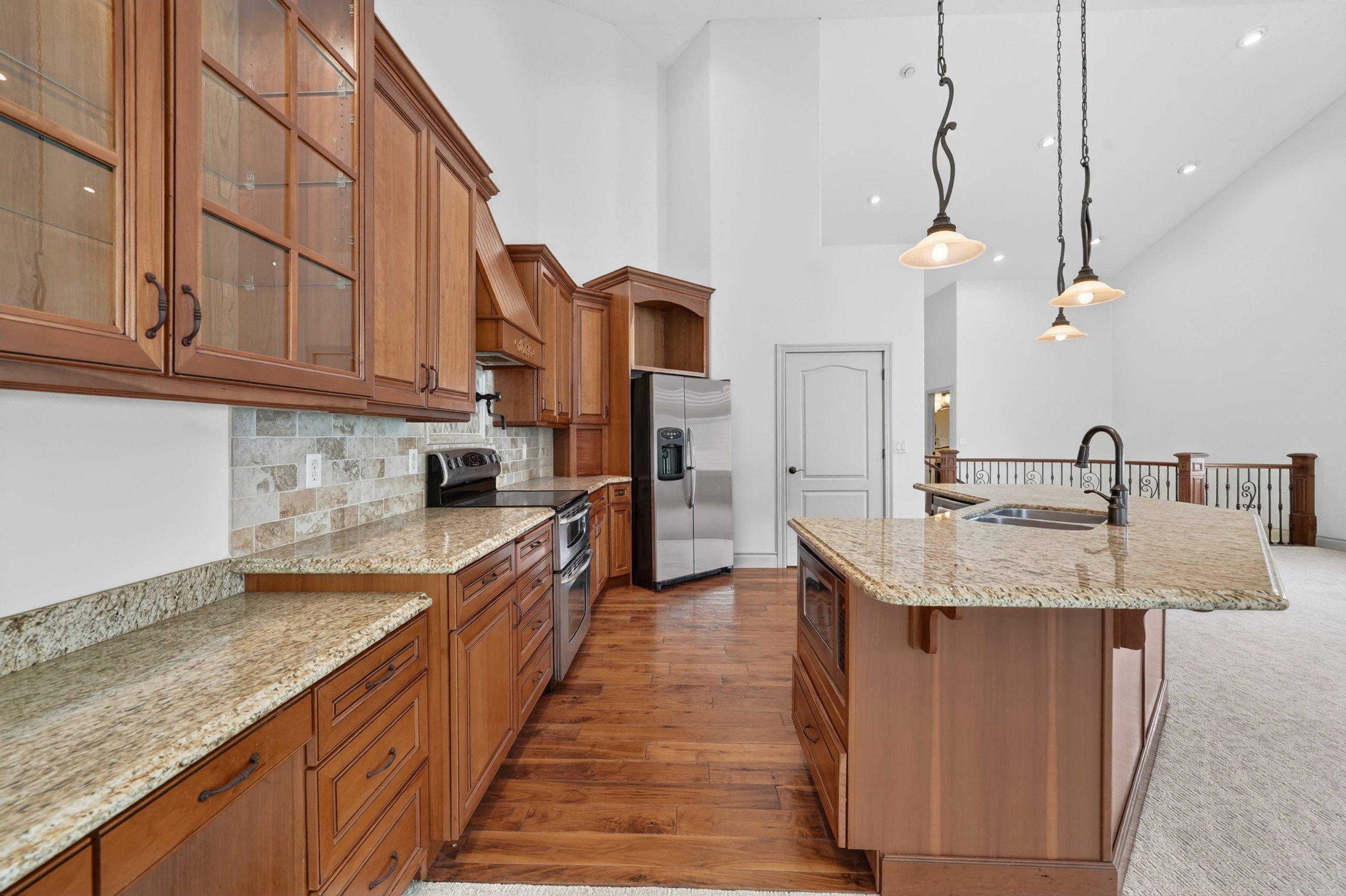 Kitchen featuring rich wood cabinetry, granite countertops, a tile backsplash, and stainless steel appliances