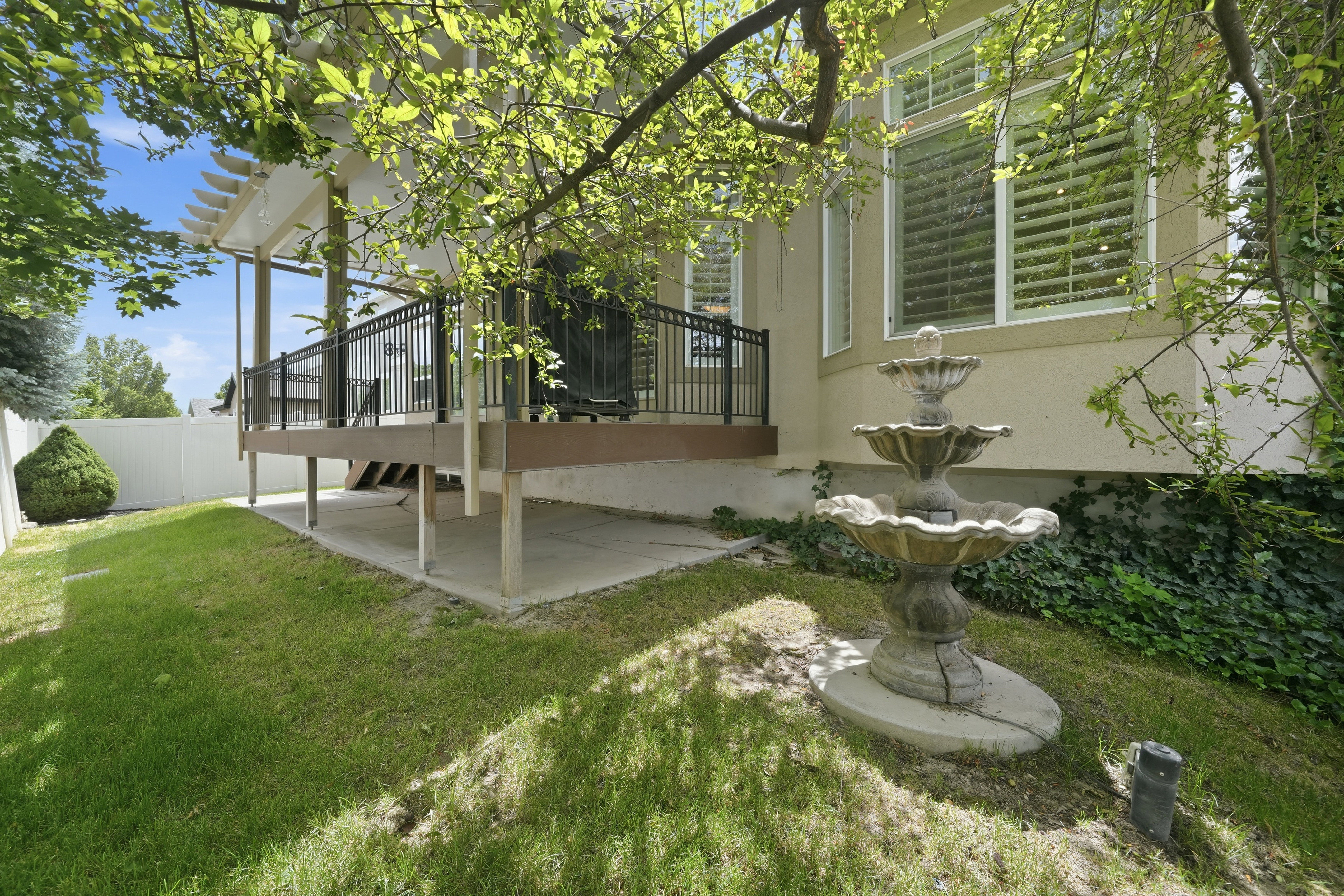Expansive backyard featuring a multi-tiered water fountain, manicured lawn, and mature trees