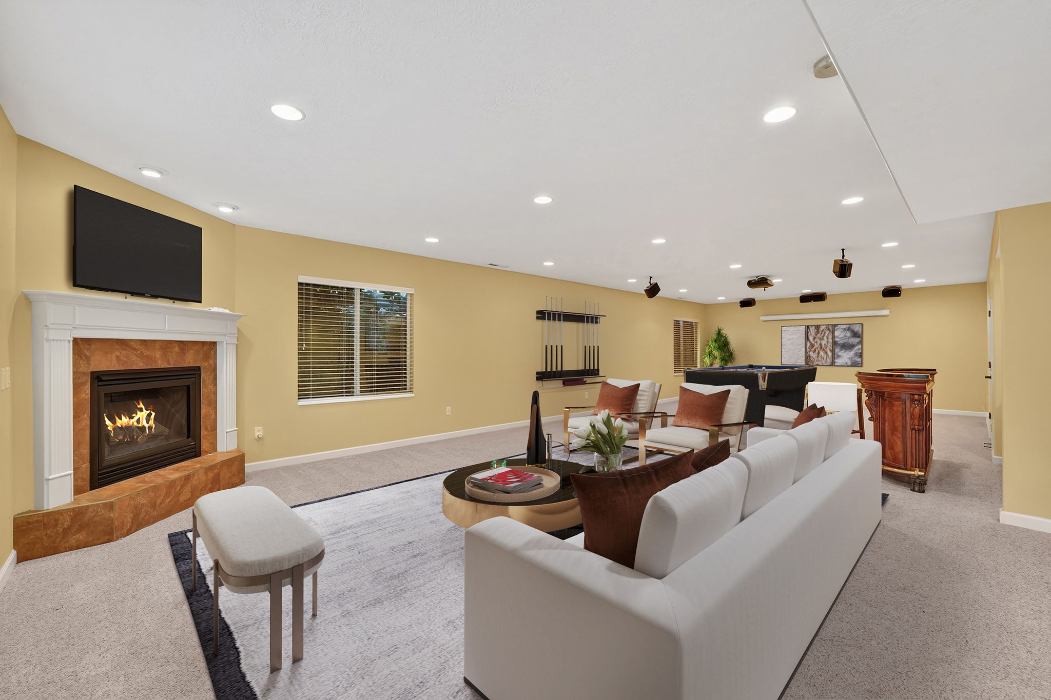 Staged great room with light colored carpet, a tiled fireplace, billiards, and recessed lighting