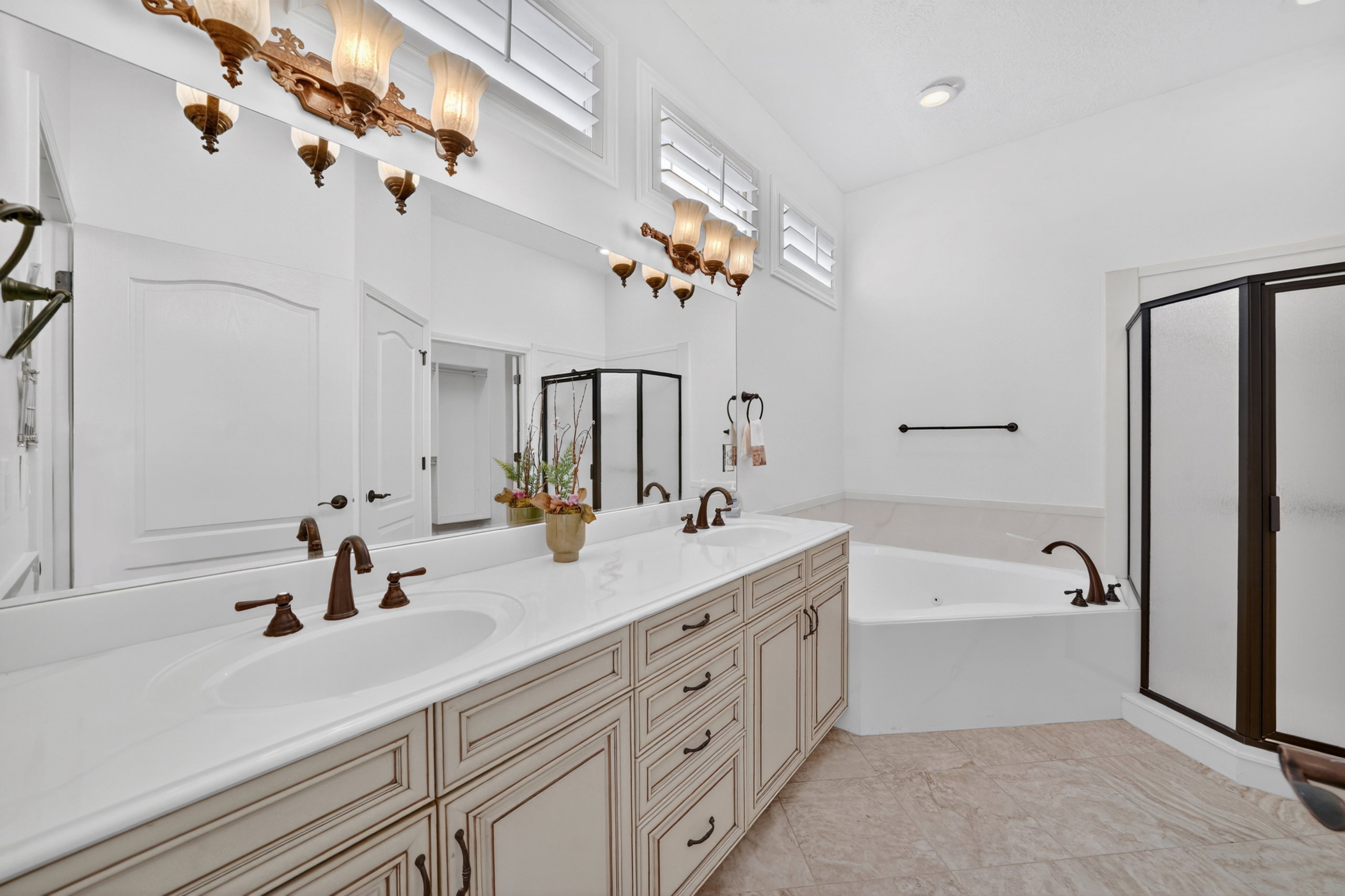 Dual vanity with integrated sinks, oil-rubbed bronze fixtures, a full-width mirror, and decorative cabinetry