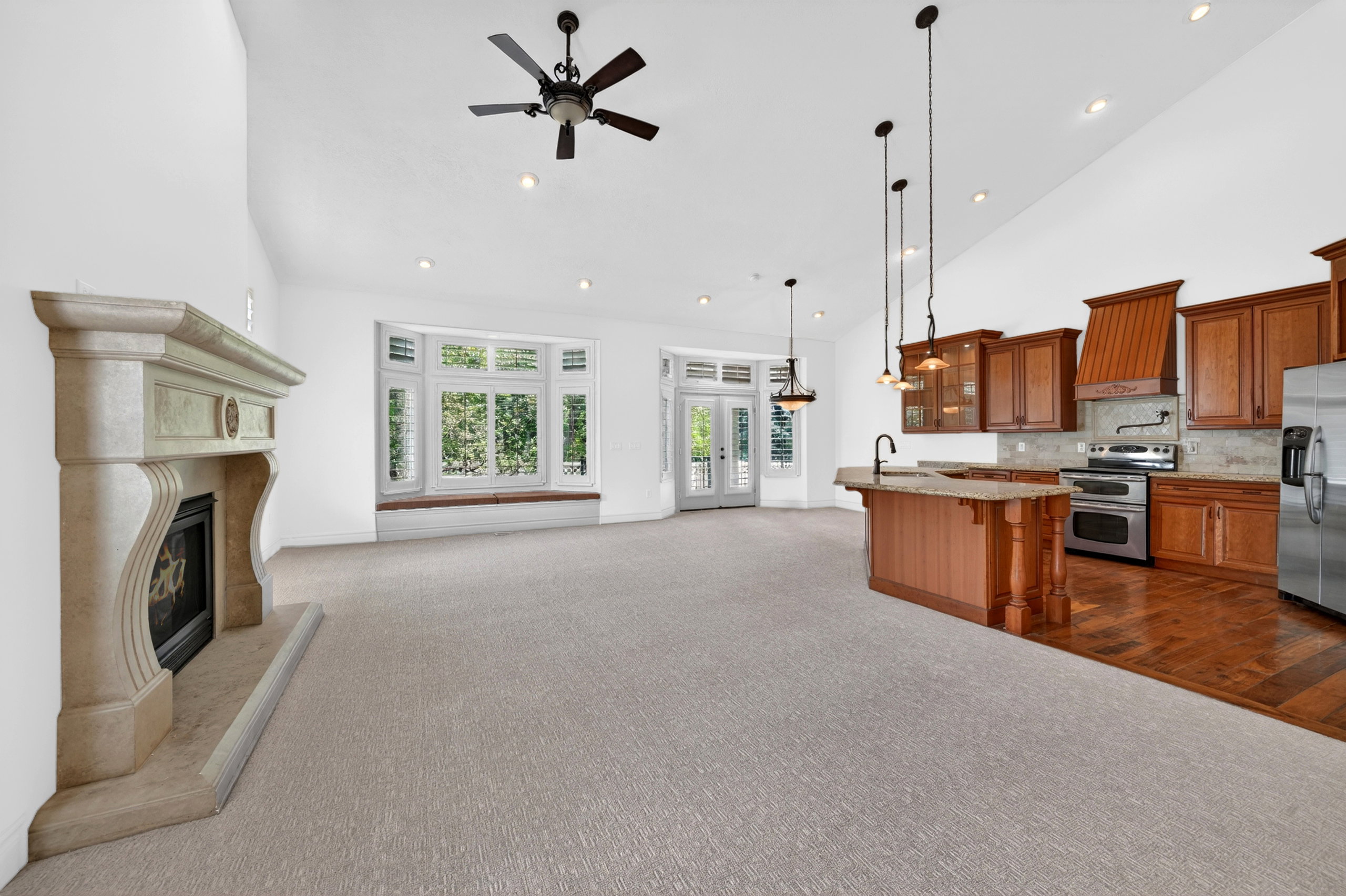 Vaulted ceilings throughout this open-concept room, featuring a stone fireplace and bay windows