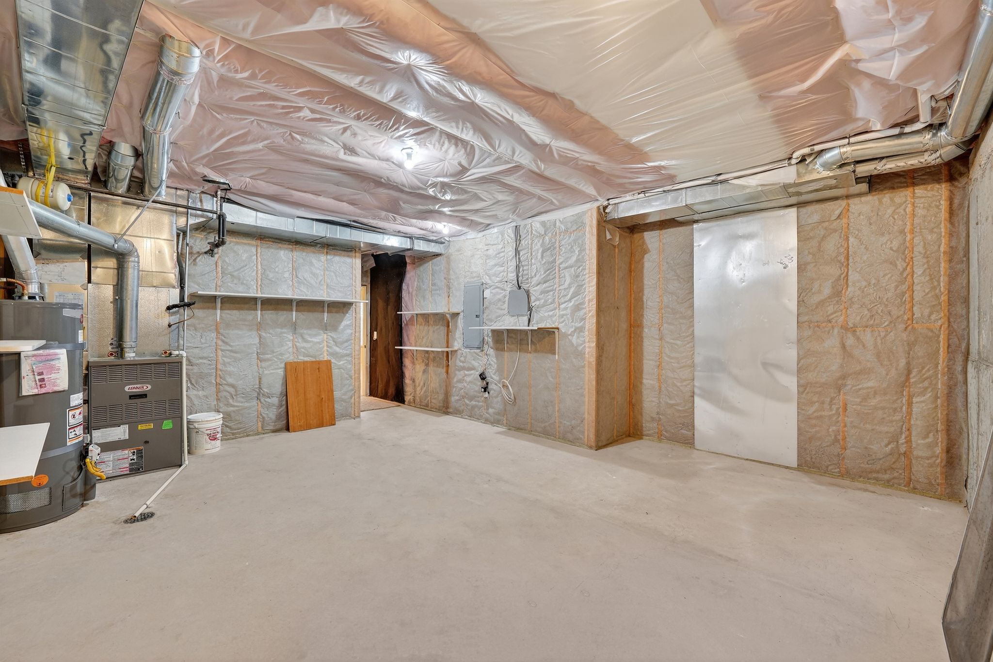 Unfinished storage room with strapped water heater and electric panel