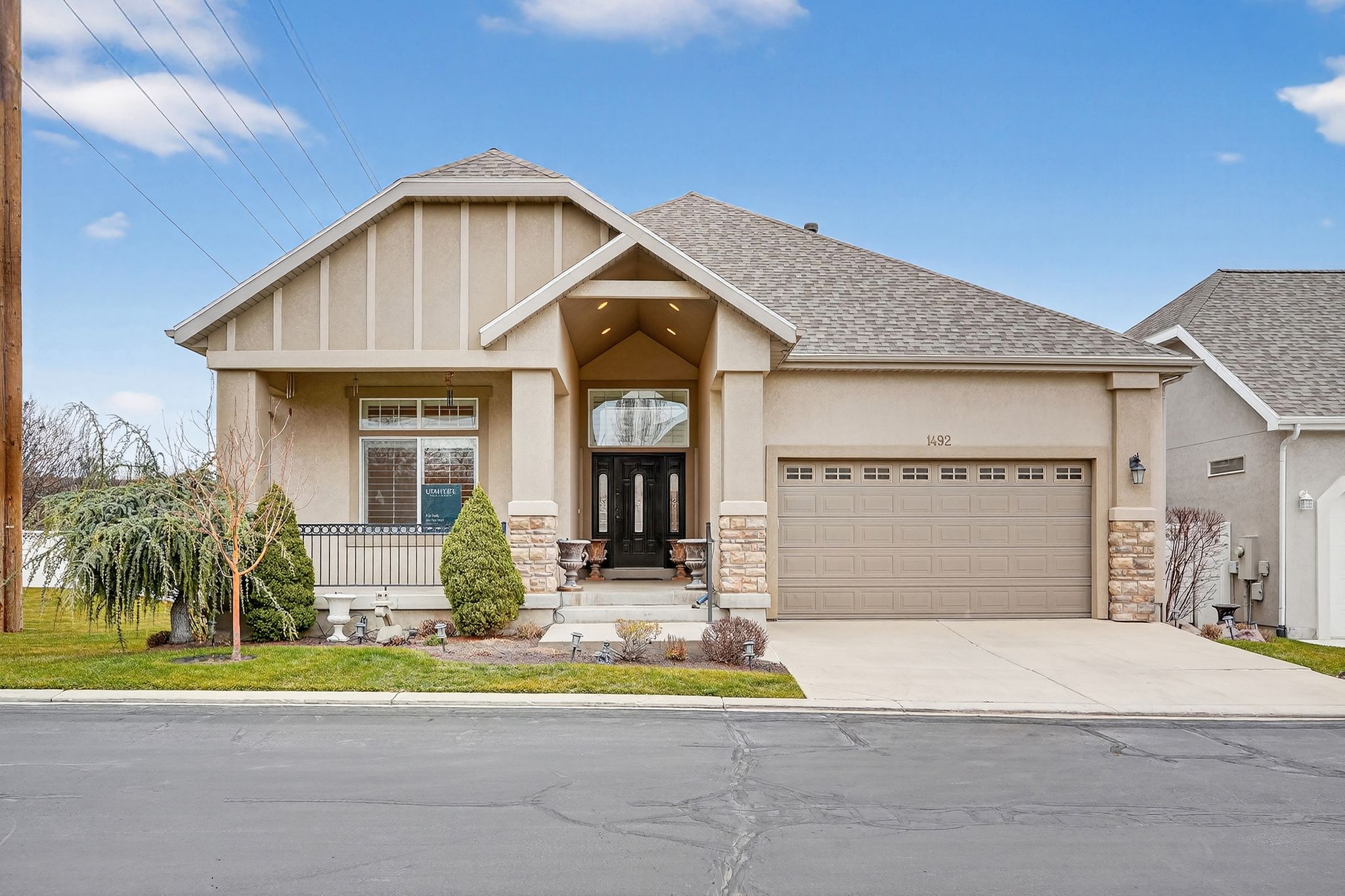 Craftsman-style house with covered porch, stone siding, driveway, stucco siding, and a garage