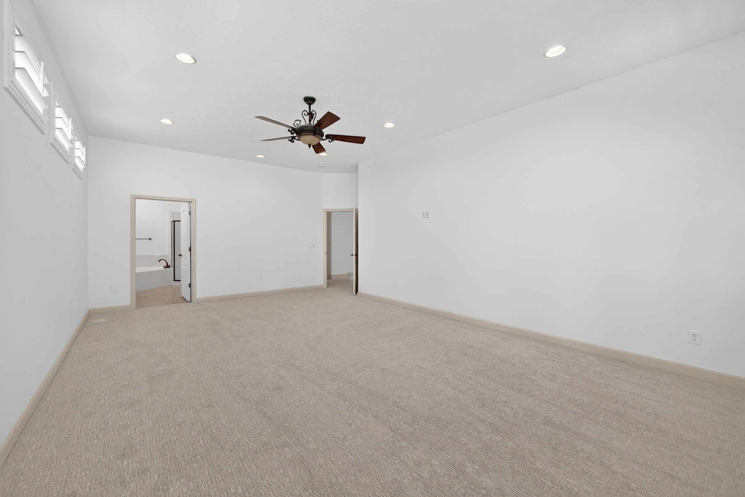 Spacious room featuring vaulted ceilings with recessed lighting, an overhead ceiling fan, and light-toned carpeting
