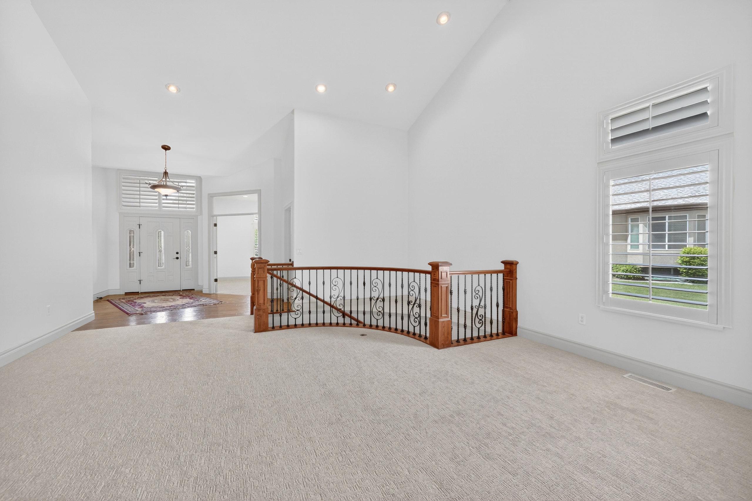 Carpeted open area with a decorative wood and wrought iron railing