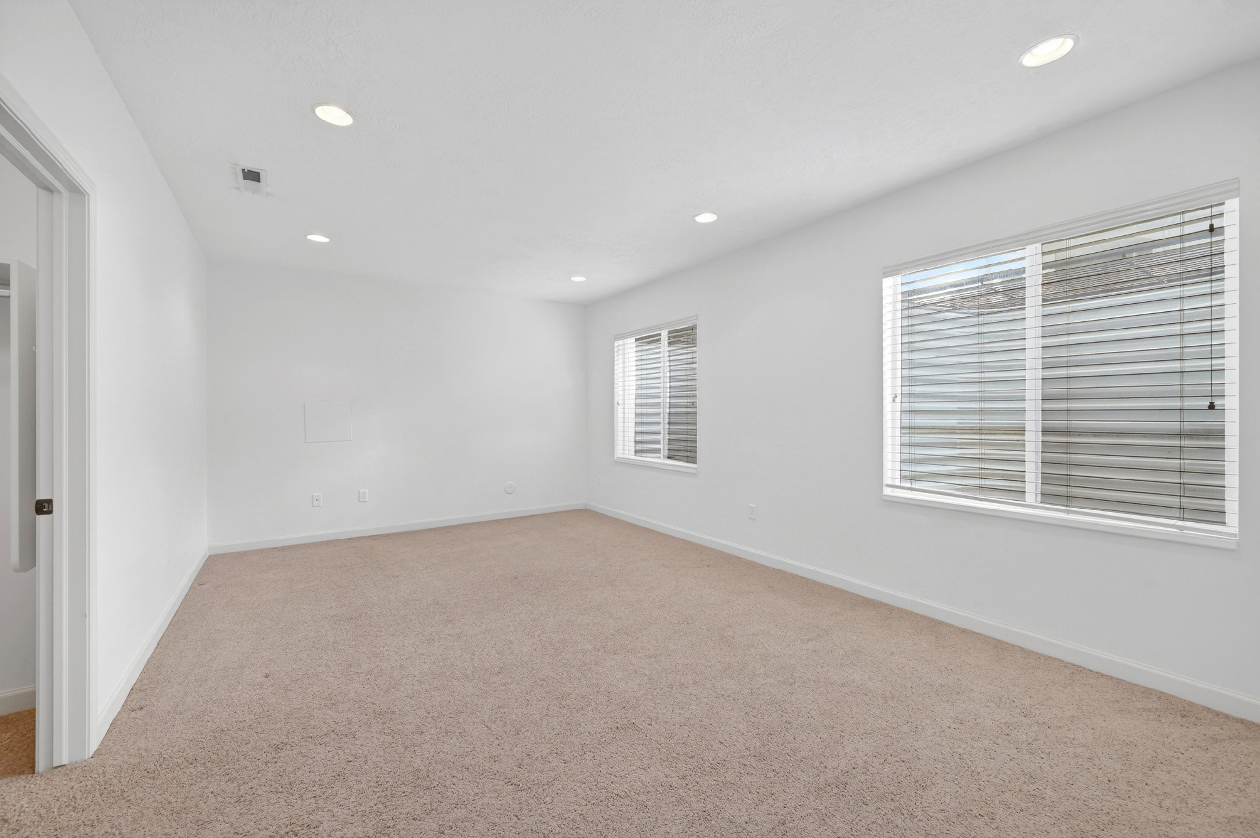Spacious room featuring neutral carpet flooring, recessed lighting, and white walls