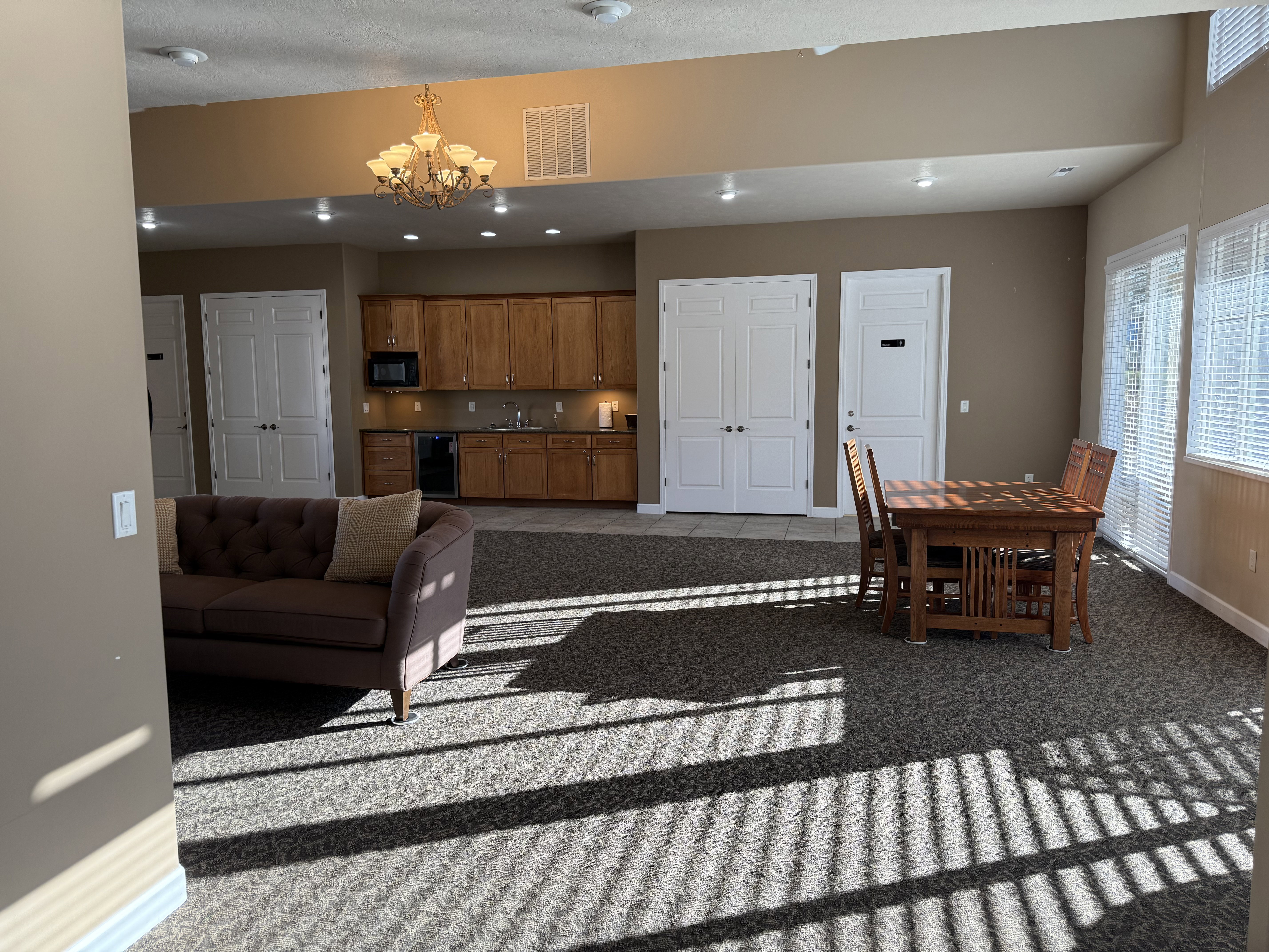 Clubhouse carpeted living area featuring baseboards and a chandelier