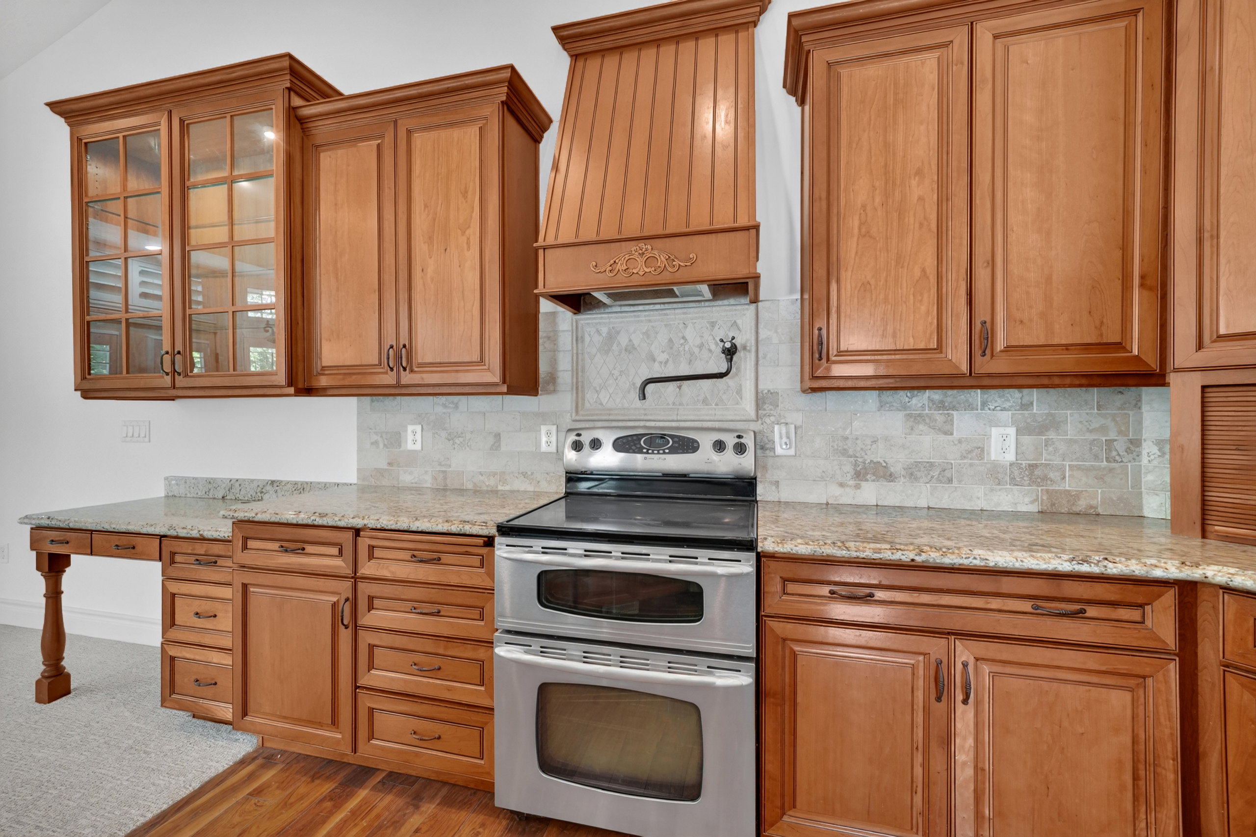 Kitchen featuring wood cabinetry, light-toned stone countertops, and a subway tile backsplash