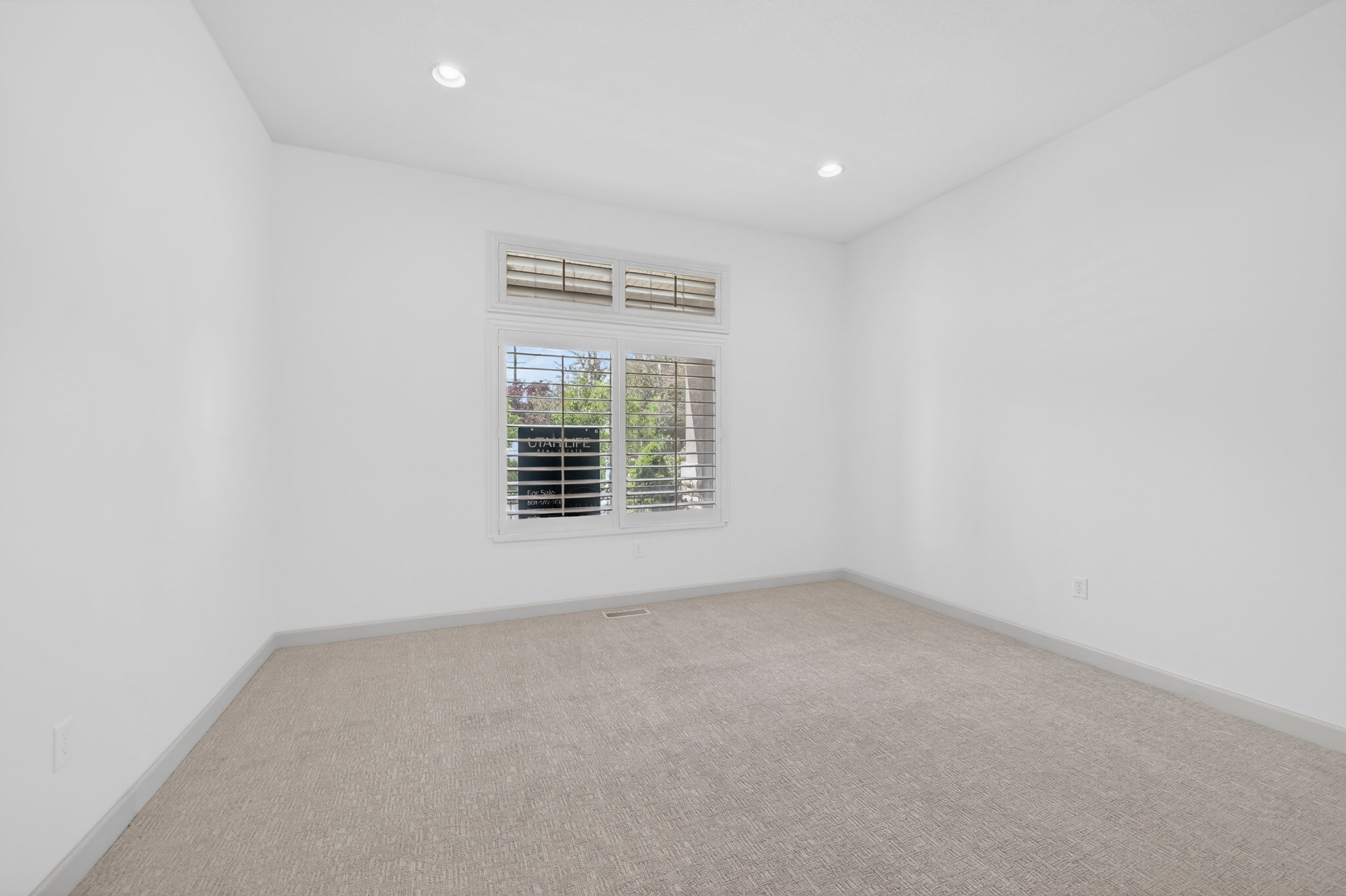 Interior space with neutral carpeting, white walls, and recessed lighting