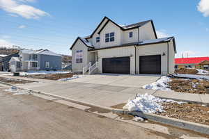 Modern farmhouse featuring board and batten siding, driveway, a residential view, a standing seam roof, and a garage