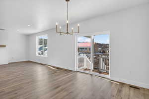 Unfurnished dining area with hanging lights and light wood-style floors