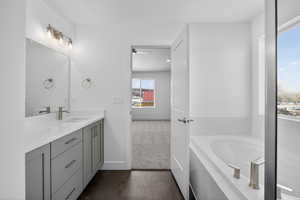 Bathroom featuring vanity, a garden tub, and dark colored carpet