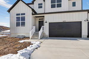 Modern farmhouse with an attached garage, board and batten siding, and concrete driveway