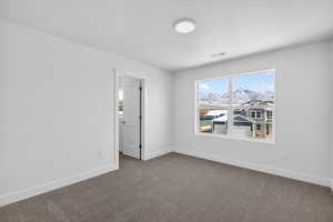 Empty room with dark colored carpet, a mountain view, and a textured ceiling