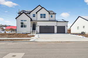 Modern farmhouse with concrete driveway, a standing seam roof, an attached garage, and board and batten siding