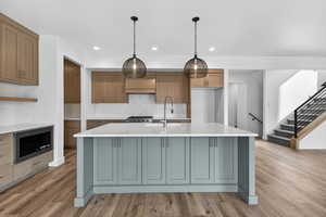 Two tone kitchen featuring pendant lighting, backsplash, light wood-style floors, light stone counters, and built in microwave