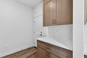 Laundry area with dark wood-type flooring and baseboards