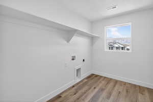 Laundry area with electric dryer hookup, light wood-style flooring, a textured ceiling, and washer hookup