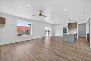 Unfurnished living room with a ceiling fan, light wood finished floors, and hanging lights
