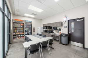 Kitchen with a drop ceiling, light countertops, modern cabinets, brown cabinetry, and black microwave