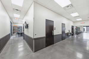 Hall featuring concrete flooring and a paneled ceiling