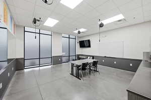 Dining space with a paneled ceiling and concrete floors