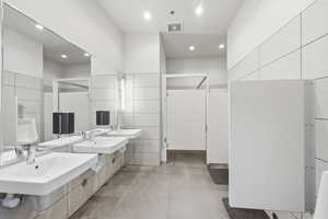 Full bath featuring concrete flooring, recessed lighting, and two vanities